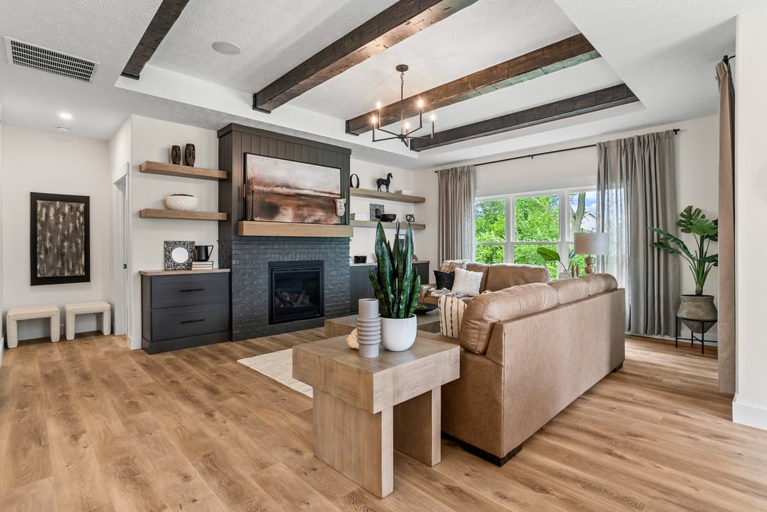 Living room with stained ceiling beams, shelving, and wood flooring