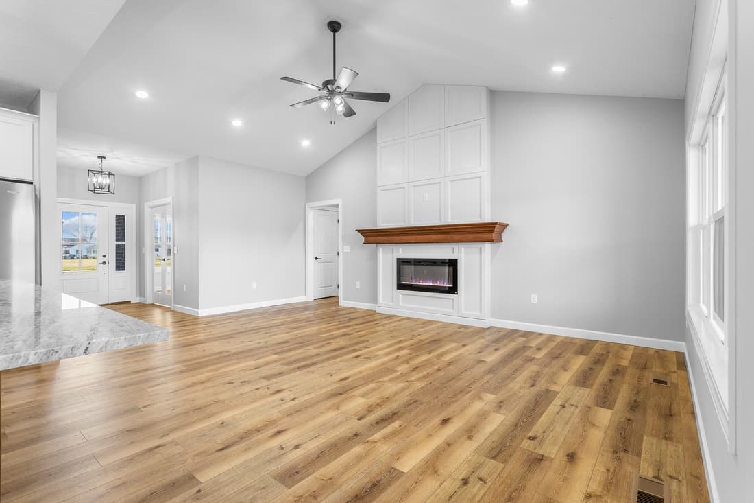 Open room showing natural wood flooring and a wood mantel