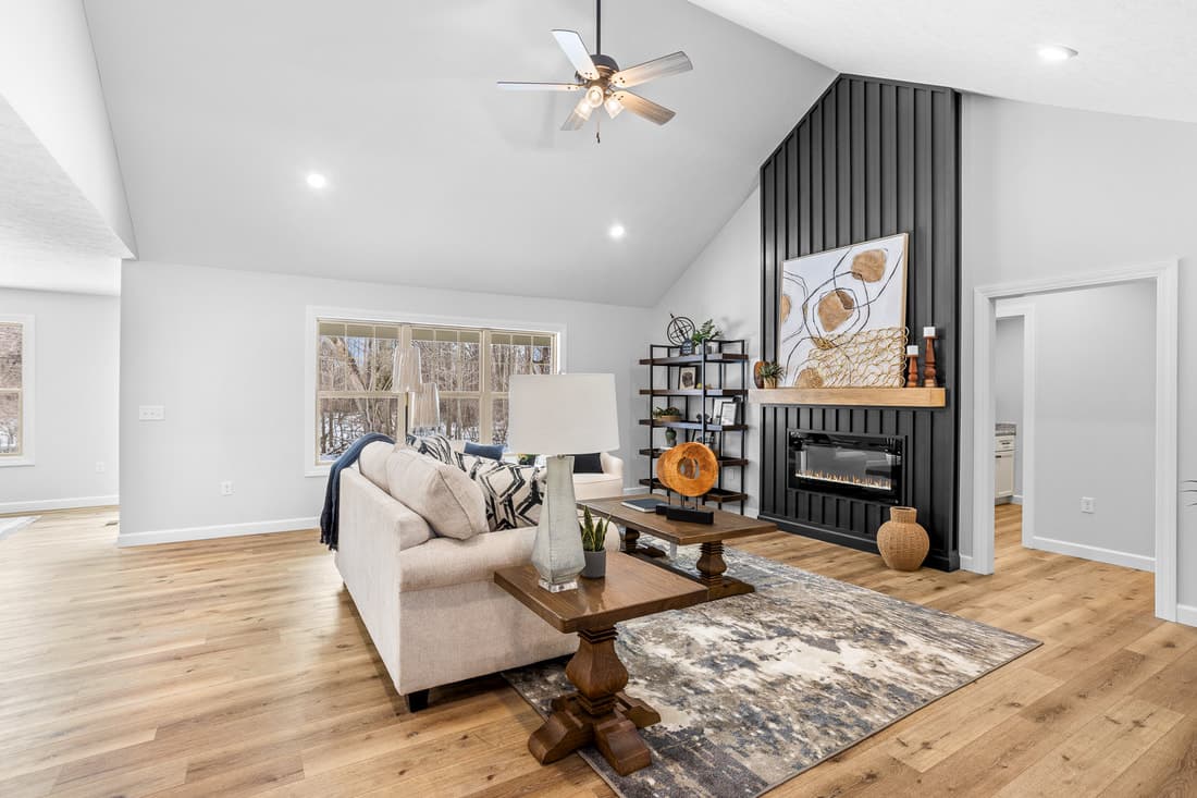 Vaulted living room with dark fireplace wall and wood mantel