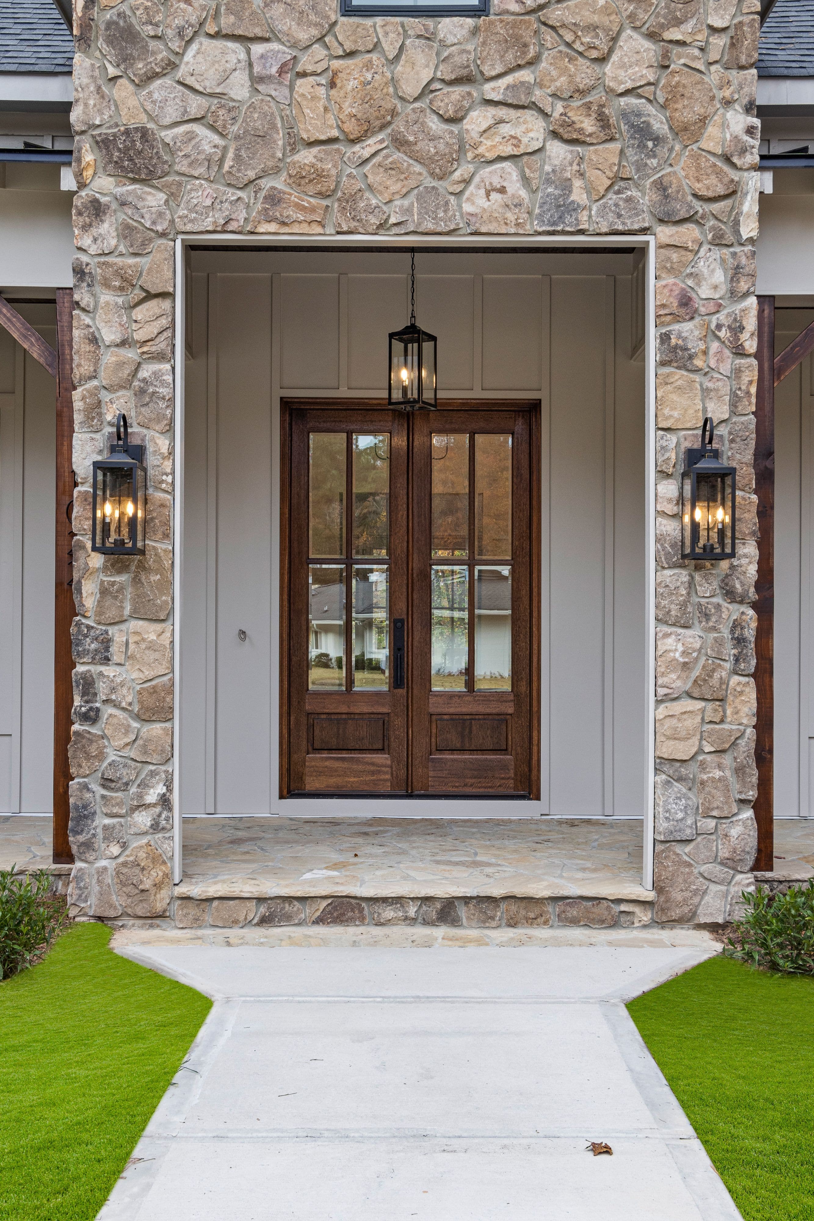 Wood double entry doors framed by stone and exterior trim